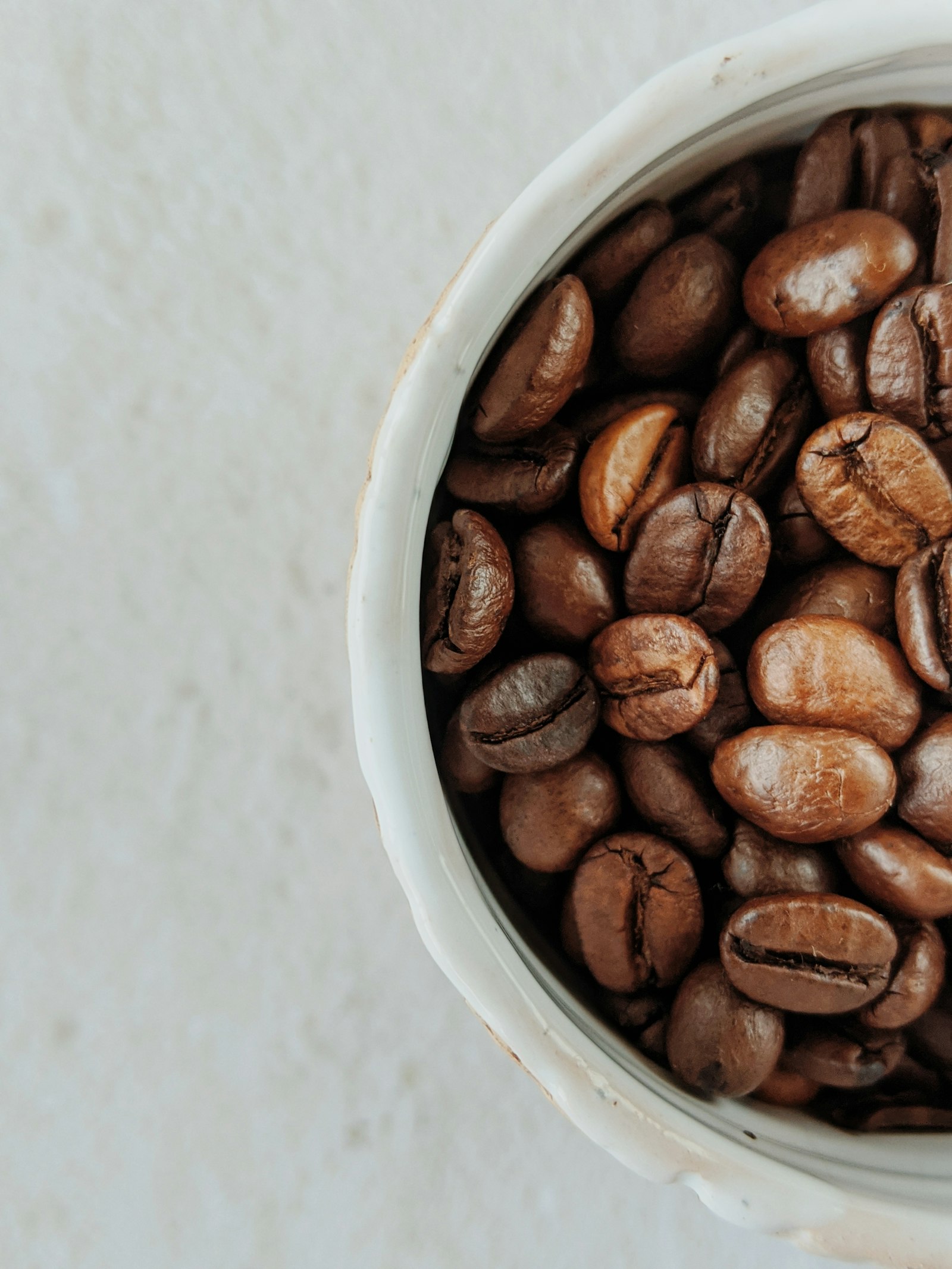 Roasted coffee beans in a rustic white ceramic bowl
