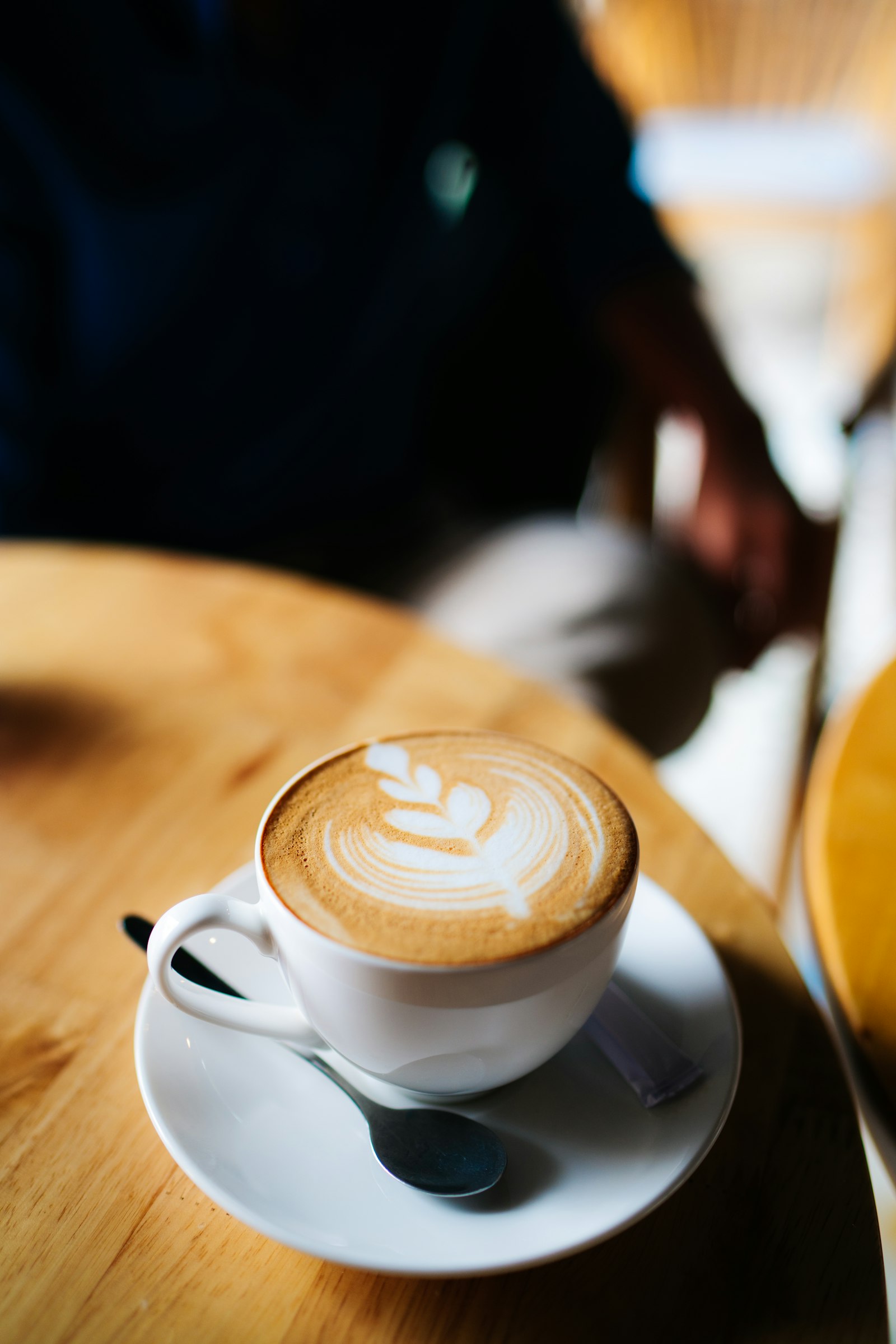 Top-down view of latte with leaf art on a wooden table
