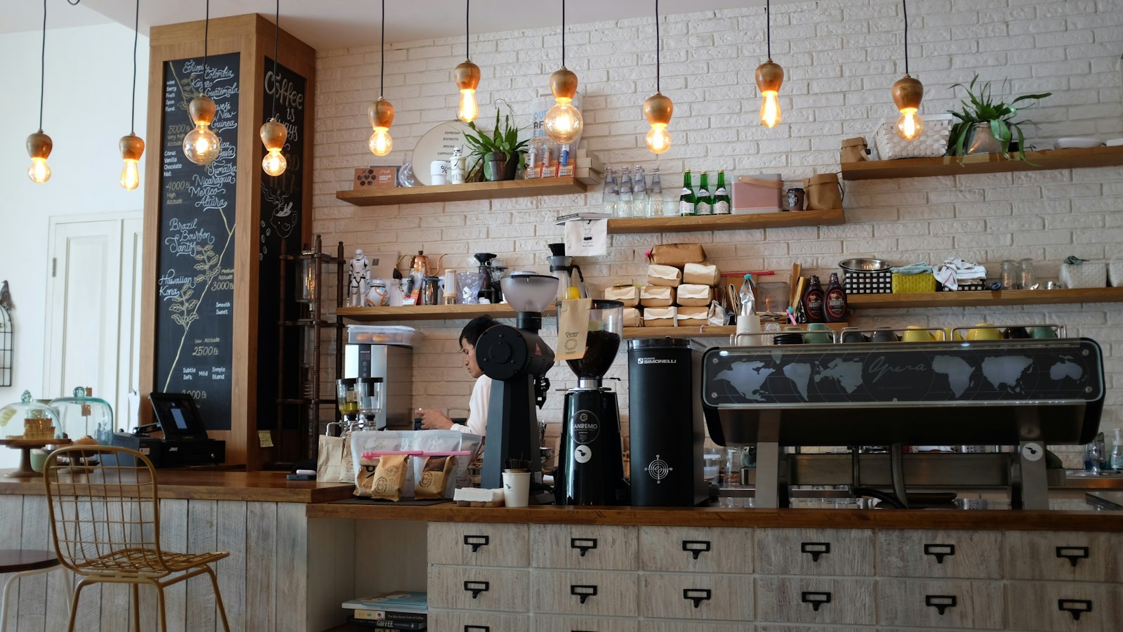Barista at work behind a coffee bar with an espresso machine